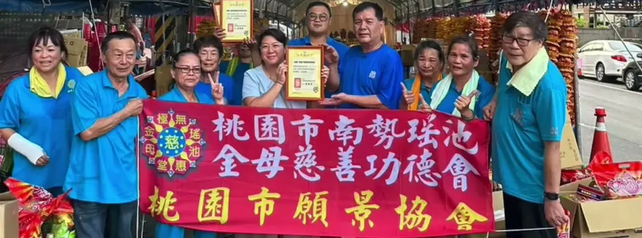協會成員與桃園市南勢瑤池金母慈善功德會成員在布條前合影