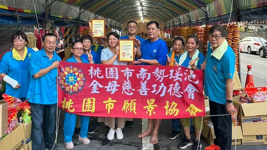 協會幹部與桃園市南勢瑤池金母慈善功德會成員在帳棚下手持布條合影
